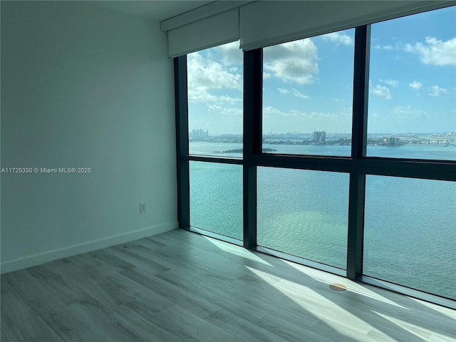 spare room featuring light wood-type flooring and a water view