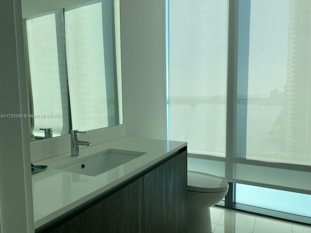 bathroom with toilet, tile patterned flooring, and vanity