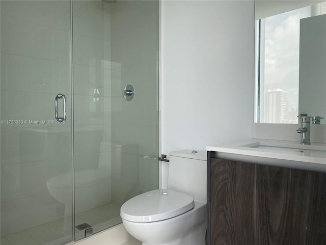 bathroom with toilet, vanity, and a shower with shower door