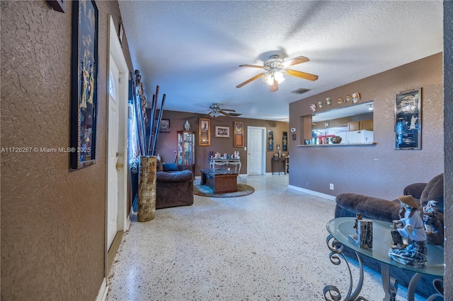 living room featuring a textured ceiling, ceiling fan, and a wood stove