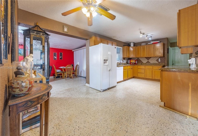 kitchen featuring a textured ceiling, sink, decorative backsplash, and white appliances