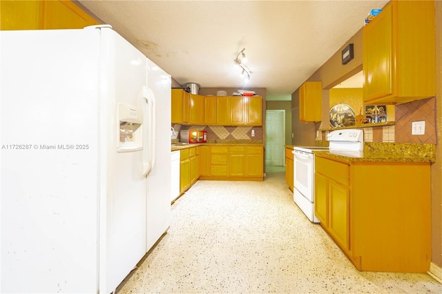 kitchen featuring decorative backsplash, light stone counters, and white appliances