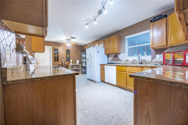 kitchen featuring backsplash, white appliances, kitchen peninsula, and dark stone countertops