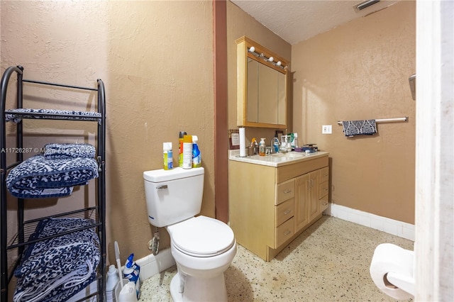 bathroom with toilet, vanity, and a textured ceiling