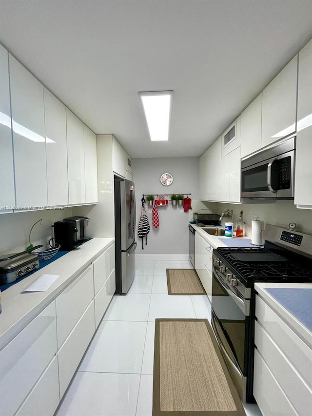 kitchen with sink, white cabinets, light tile patterned flooring, and appliances with stainless steel finishes