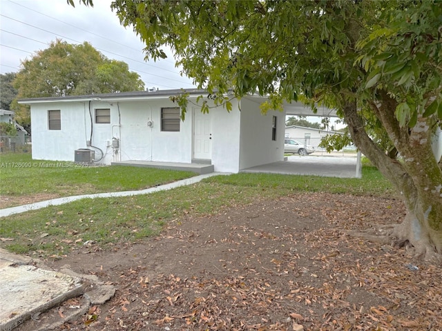 rear view of house featuring a lawn, a carport, and central AC unit