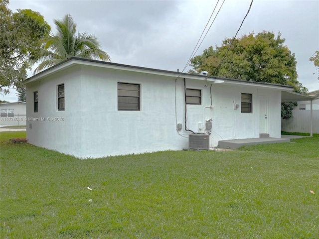 rear view of property featuring central AC unit and a yard