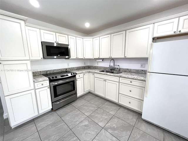 kitchen with stainless steel appliances, white cabinetry, sink, and light stone counters