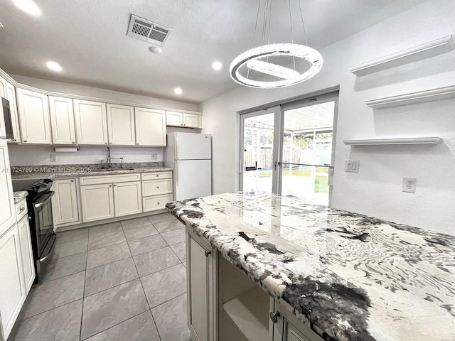 kitchen with electric stove, sink, white refrigerator, light stone countertops, and decorative light fixtures