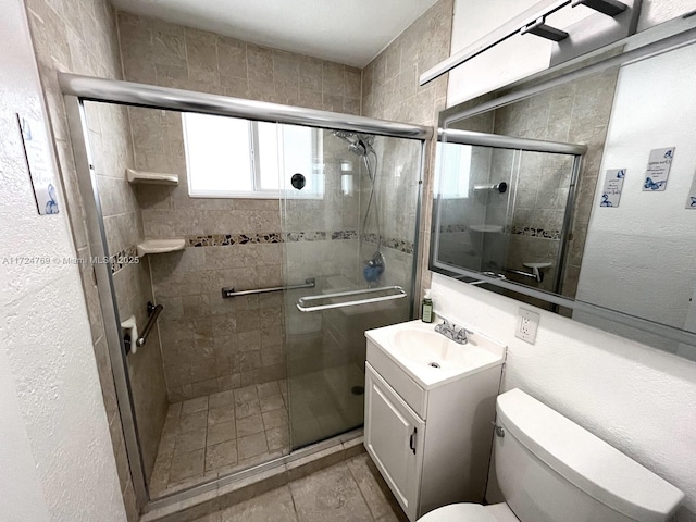 bathroom featuring vanity, tile patterned floors, a shower with door, and toilet