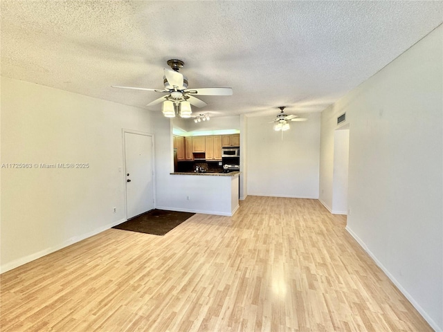 unfurnished living room with a textured ceiling, light hardwood / wood-style floors, and ceiling fan