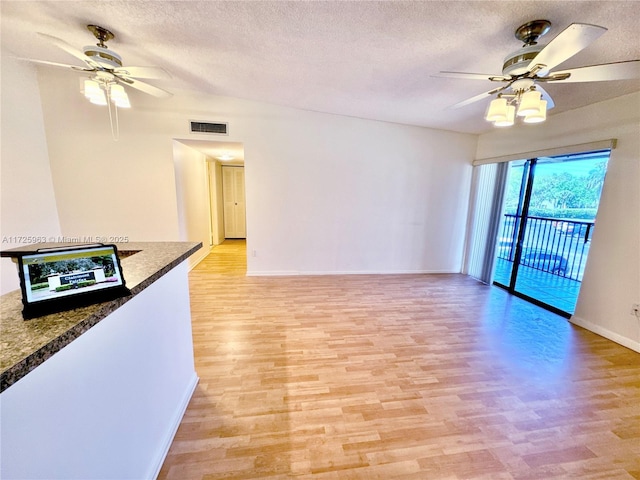 empty room with ceiling fan, a textured ceiling, and light wood-type flooring