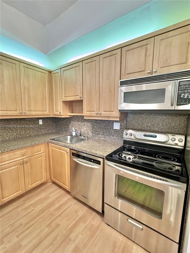 kitchen with sink, a textured ceiling, light wood-type flooring, appliances with stainless steel finishes, and decorative backsplash