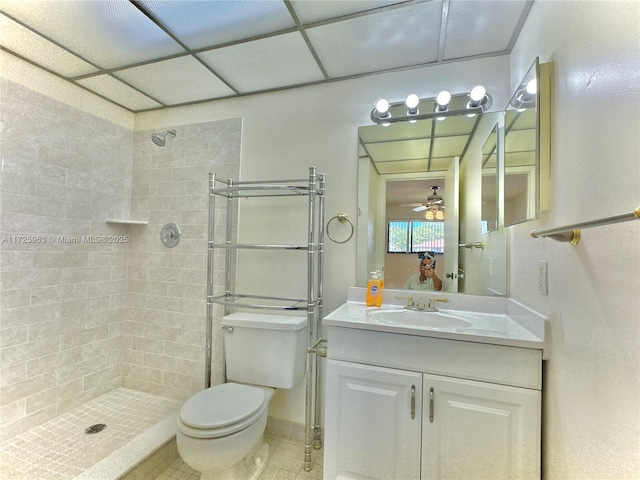 bathroom featuring vanity, a paneled ceiling, toilet, and tiled shower