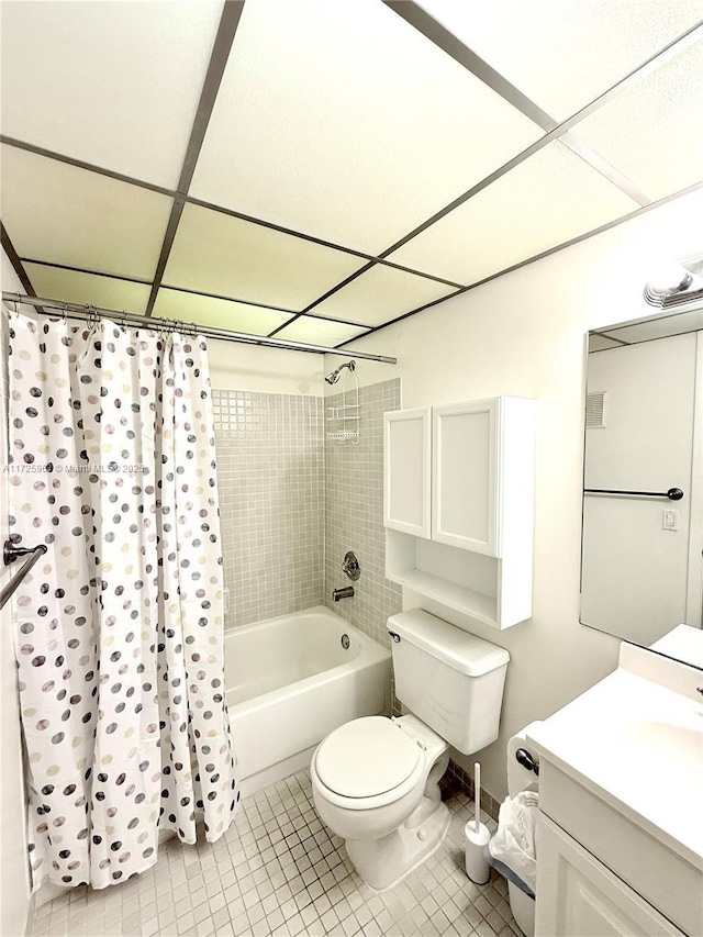 full bathroom with a paneled ceiling, shower / bath combination with curtain, tile patterned flooring, vanity, and toilet