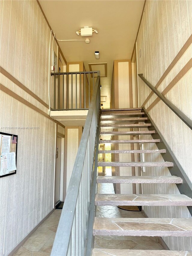 staircase featuring wood walls