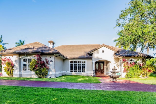 view of front of property featuring a tiled roof, a front lawn, and stucco siding