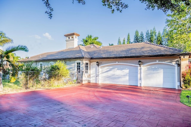 view of front of home with a garage, decorative driveway, fence, and stucco siding