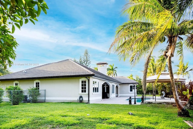 rear view of property featuring a yard, stucco siding, a gazebo, a patio area, and fence