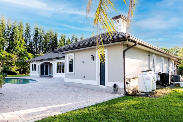 back of house with central AC, french doors, stucco siding, an outdoor pool, and a patio area