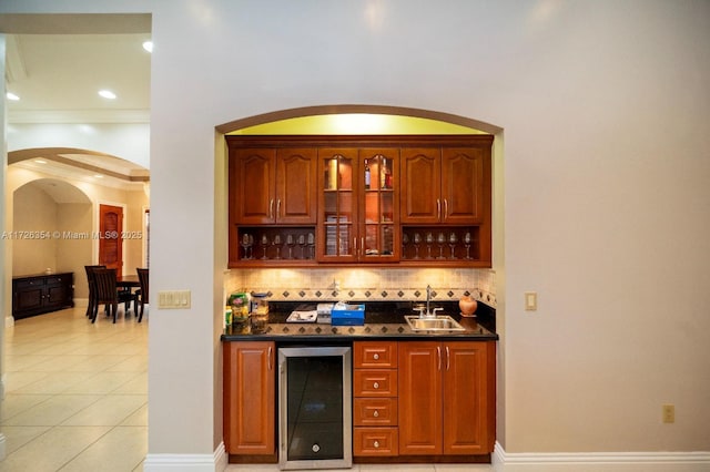 bar featuring light tile patterned floors, beverage cooler, a sink, backsplash, and wet bar