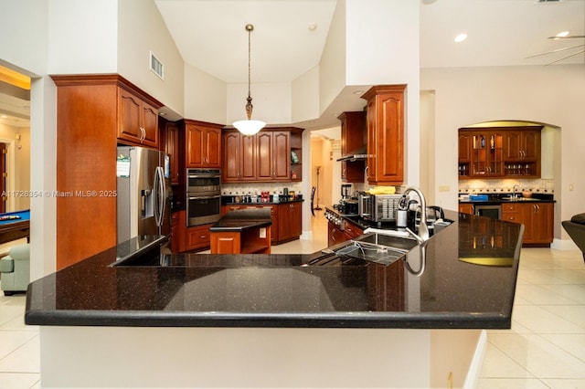 kitchen with light tile patterned floors, a peninsula, visible vents, appliances with stainless steel finishes, and decorative backsplash