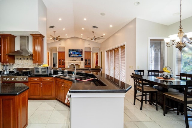 kitchen featuring light tile patterned floors, a peninsula, a sink, open floor plan, and wall chimney range hood