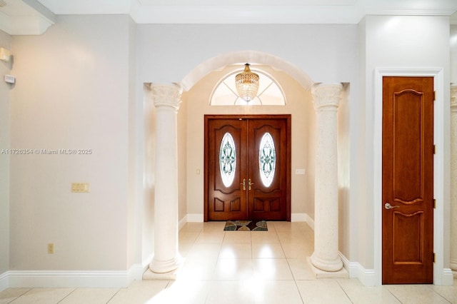 tiled foyer entrance featuring arched walkways, baseboards, and ornate columns