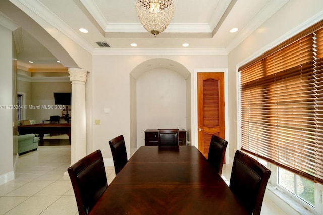 dining area featuring arched walkways, a tray ceiling, light tile patterned floors, and ornate columns