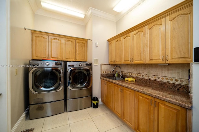 laundry area featuring cabinet space, light tile patterned floors, washer and clothes dryer, ornamental molding, and a sink