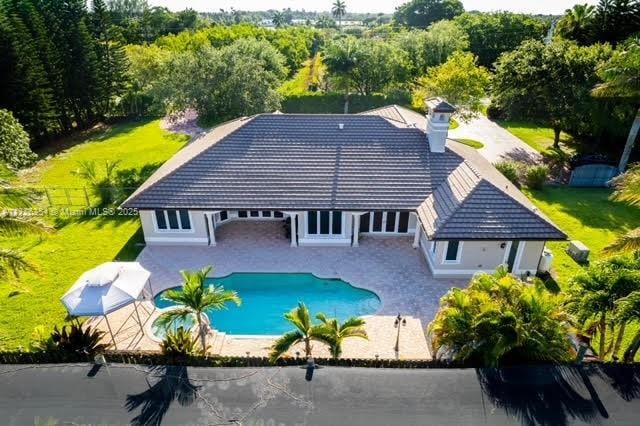 back of house with a patio, a tile roof, fence, and an outdoor pool