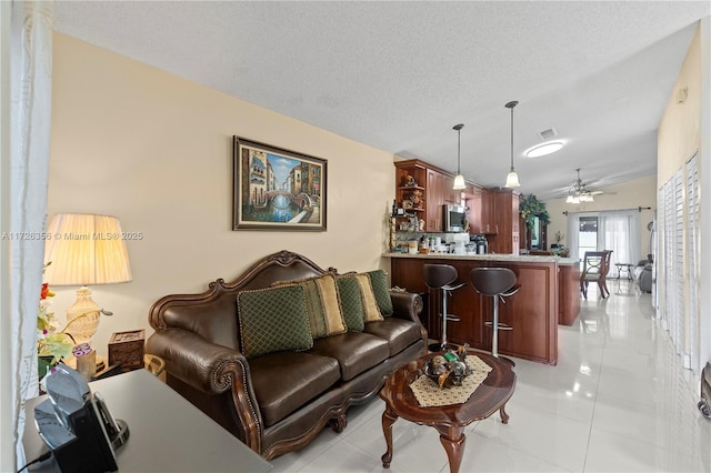 living room with ceiling fan, a textured ceiling, light tile patterned floors, and vaulted ceiling