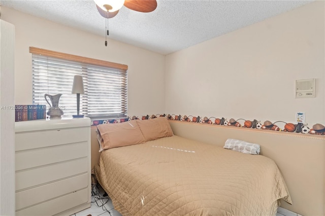 bedroom with ceiling fan, a textured ceiling, and light tile patterned floors