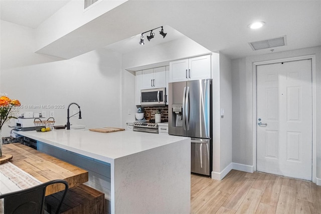 kitchen with visible vents, a sink, stainless steel appliances, white cabinets, and light wood-type flooring