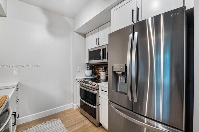 kitchen featuring white cabinets, appliances with stainless steel finishes, backsplash, and light hardwood / wood-style flooring