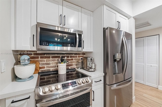 kitchen featuring stainless steel appliances, white cabinetry, visible vents, and light countertops