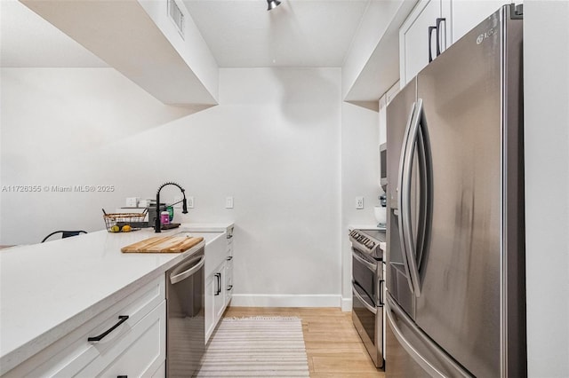 kitchen with visible vents, light wood-style flooring, white cabinetry, appliances with stainless steel finishes, and light countertops