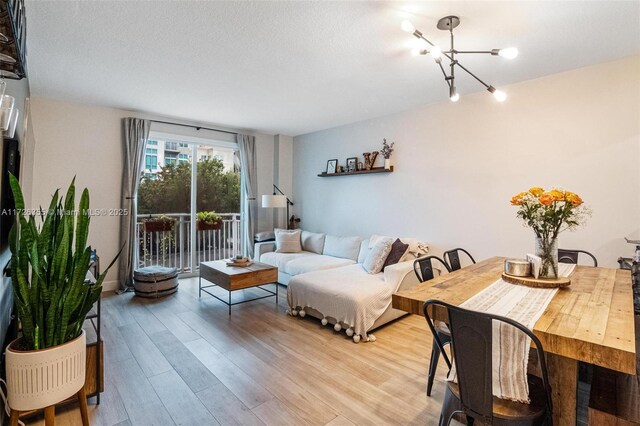 living room featuring a textured ceiling, light hardwood / wood-style flooring, and an inviting chandelier