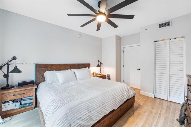 bedroom featuring ceiling fan, light hardwood / wood-style flooring, and a closet