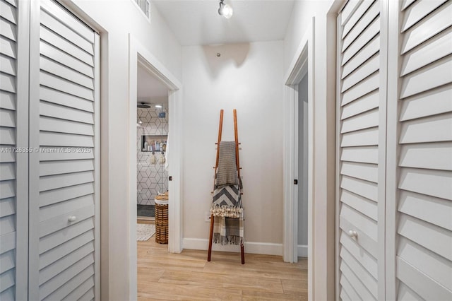 hallway with visible vents, baseboards, and light wood-style flooring