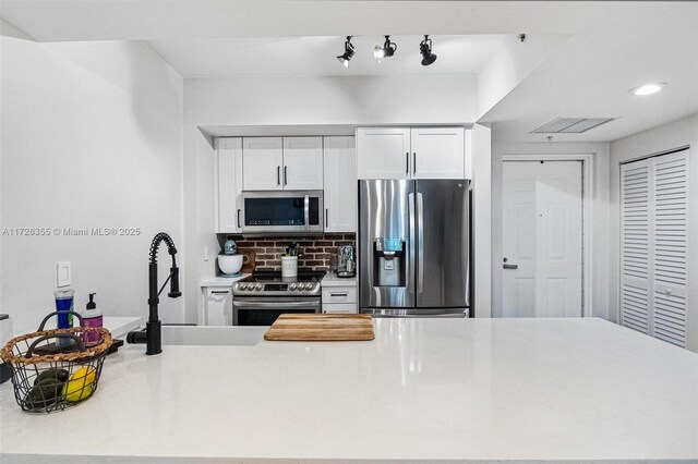 kitchen featuring white cabinets, appliances with stainless steel finishes, backsplash, and sink