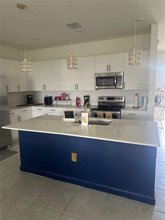 kitchen with light tile patterned floors, pendant lighting, white cabinets, and stainless steel appliances