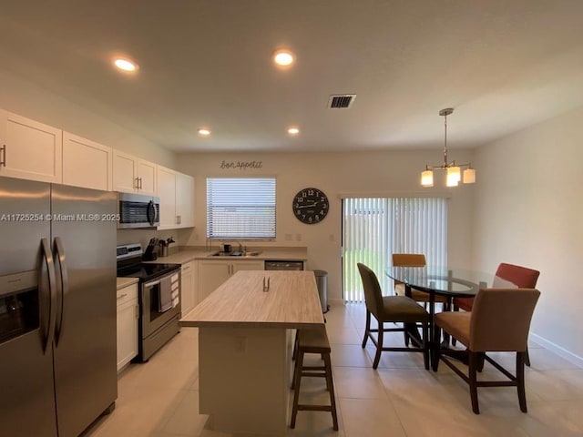 kitchen with sink, a center island, white cabinetry, and appliances with stainless steel finishes