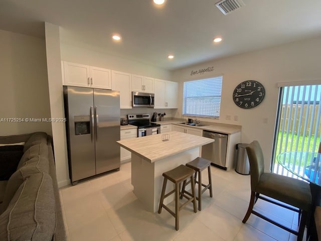 kitchen with stainless steel appliances, sink, white cabinets, a center island, and a breakfast bar area