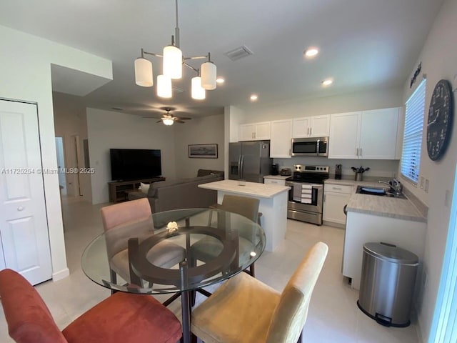 dining area featuring ceiling fan with notable chandelier and sink