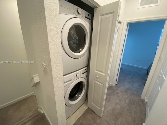 washroom featuring stacked washer and dryer and dark carpet