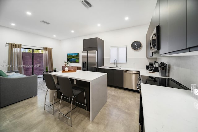 kitchen with a breakfast bar, appliances with stainless steel finishes, sink, and a center island