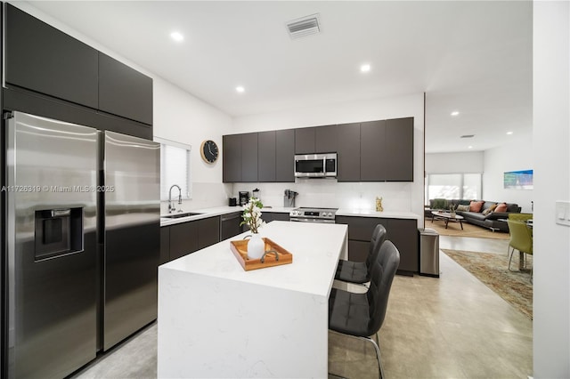 kitchen with a kitchen breakfast bar, appliances with stainless steel finishes, sink, and a center island