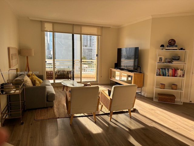 living area with crown molding, wood finished floors, baseboards, and expansive windows