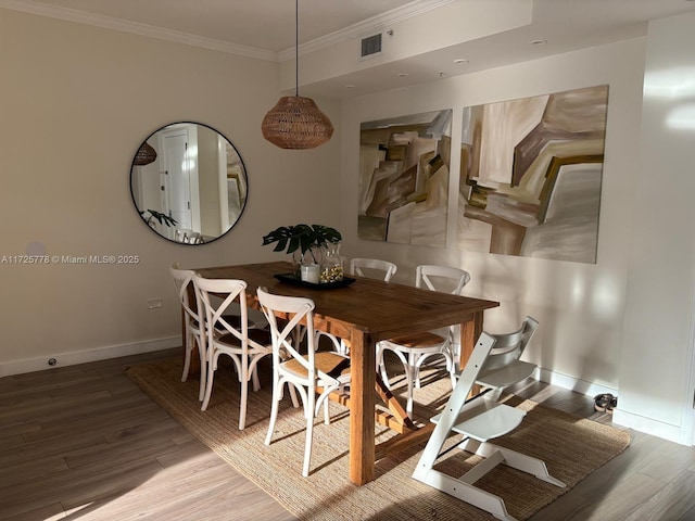 dining area with ornamental molding, wood finished floors, visible vents, and baseboards